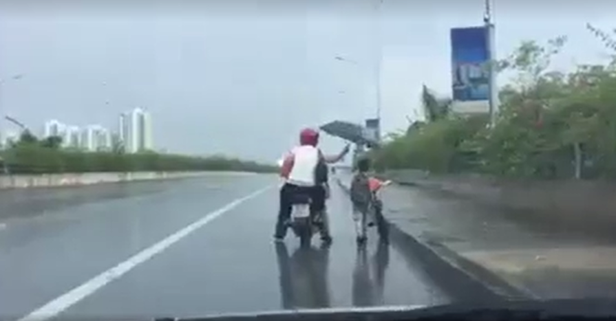 Clip cặp đôi đi xe máy đội mưa để che ô cho bé trai dắt xe đạp gây xúc động